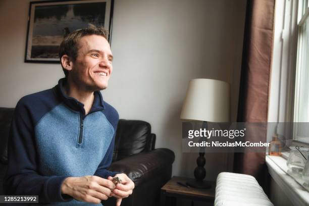 autistische trans-mann zu hause lächelnd, wie er aus dem fenster schaut - erwachsene person stock-fotos und bilder