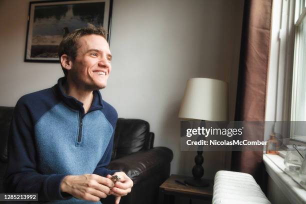 hombre trans autista en casa sonriendo mientras mira por la ventana - adult fotografías e imágenes de stock