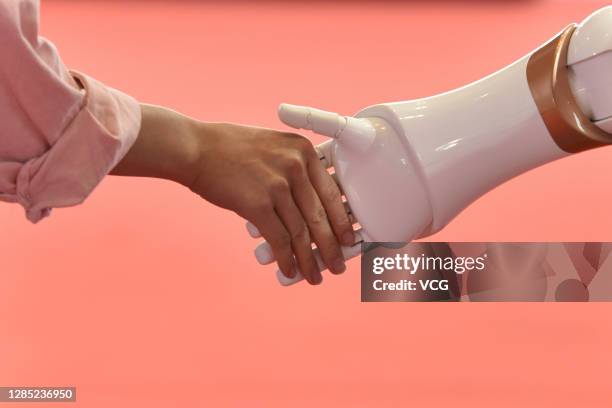 Visitor shakes hands with a robot during the China Hi-Tech Fair 2020 at the Shenzhen Convention & Exhibition Center on November 11, 2020 in Shenzhen,...