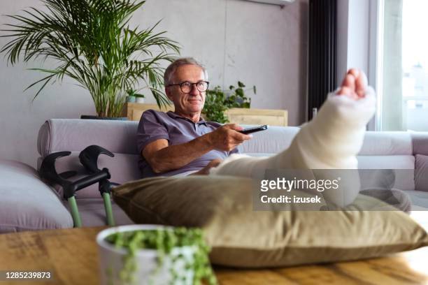 senior man with broken leg at home - old man feet stock pictures, royalty-free photos & images