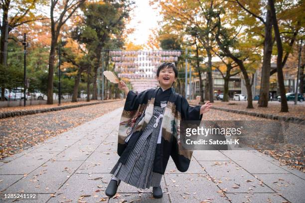 happy little boy in 'hakama' traditional japanese outfit dancing on street for shichi go san event - shichi go san stock pictures, royalty-free photos & images
