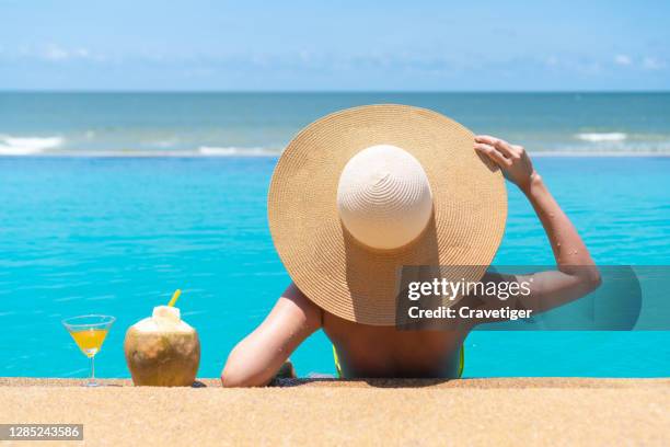 asian women relaxing in swimming pool summer holiday on beach.she feels relaxation in swimming pool summer holiday concept - women tanning beach drink stock-fotos und bilder