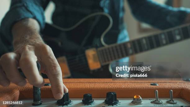 rockgitarrist spielt gitarre zu hause, pumpenlautstärke nach oben - lautstärkeregler stock-fotos und bilder