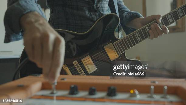 rock guitarist playing guitar at home, plugging in - guitar amp stock pictures, royalty-free photos & images