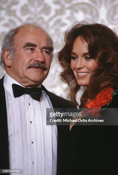 American actor Ed Asner and American actress Catherine Bach, wearing a black outfit with fake red flower decoration, attend the 40th Annual Golden...