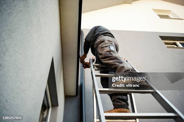 manual worker on roof installing metal tile - metallic shoe stock pictures, royalty-free photos & images