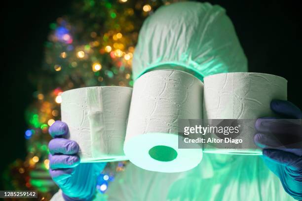 unrecognisable scientist holding three rolls of toilet paper.  there is a decorated christmas tree in the background. - traveler's diarrhoea stock pictures, royalty-free photos & images