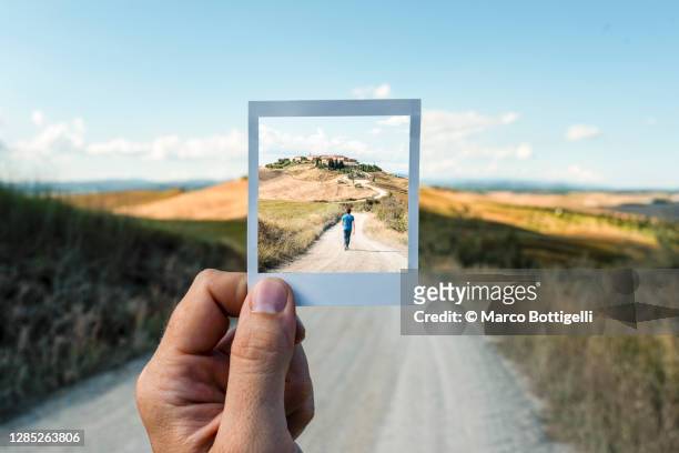personal perspective of polaroid picture overlapping a country road in tuscany - focus concept stock-fotos und bilder