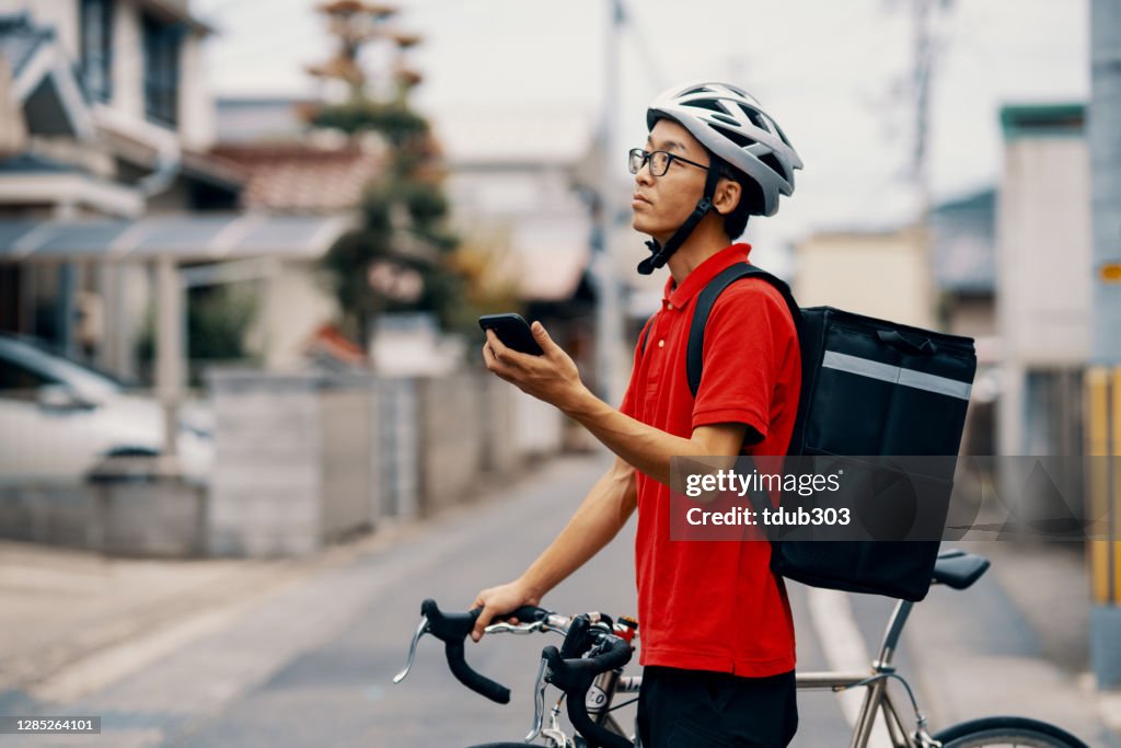 住所や目的地を探して自転車で食べ物を配達する中期の成��人男性