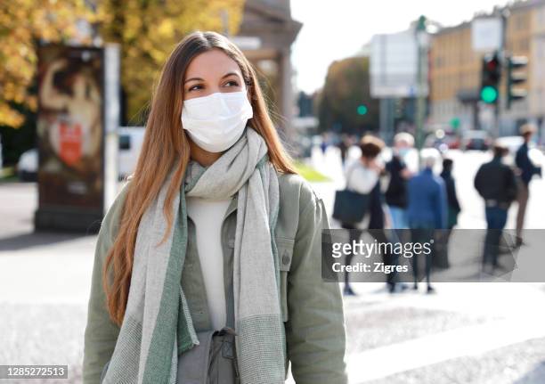 close-up of young woman wearing mask in city during winter - persona in secondo piano foto e immagini stock