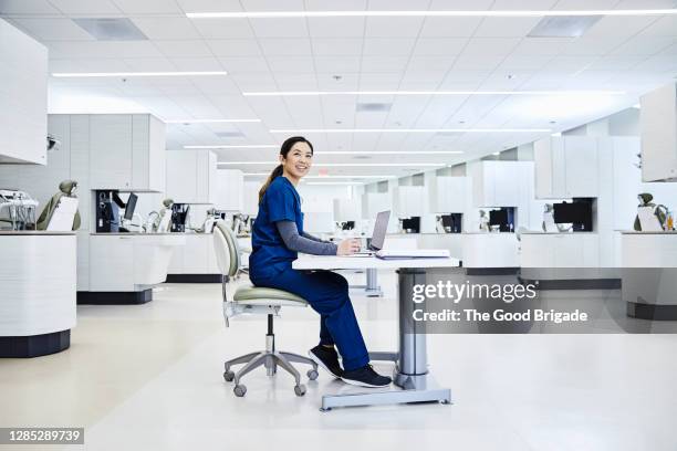 hygienist sitting at desk in dental clinic - nurse full length stock pictures, royalty-free photos & images