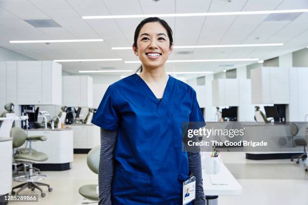 portrait of  female dentist standing in clinic - medical scrubs fotografías e imágenes de stock