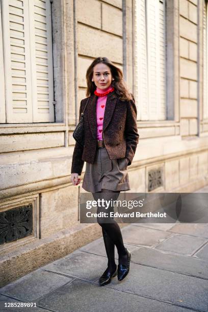 Therese Hellström wears earrings, a brown blazer jacket from Anine Bing, a pink and red turtleneck knit pullover with ruffle and printed hearts from...