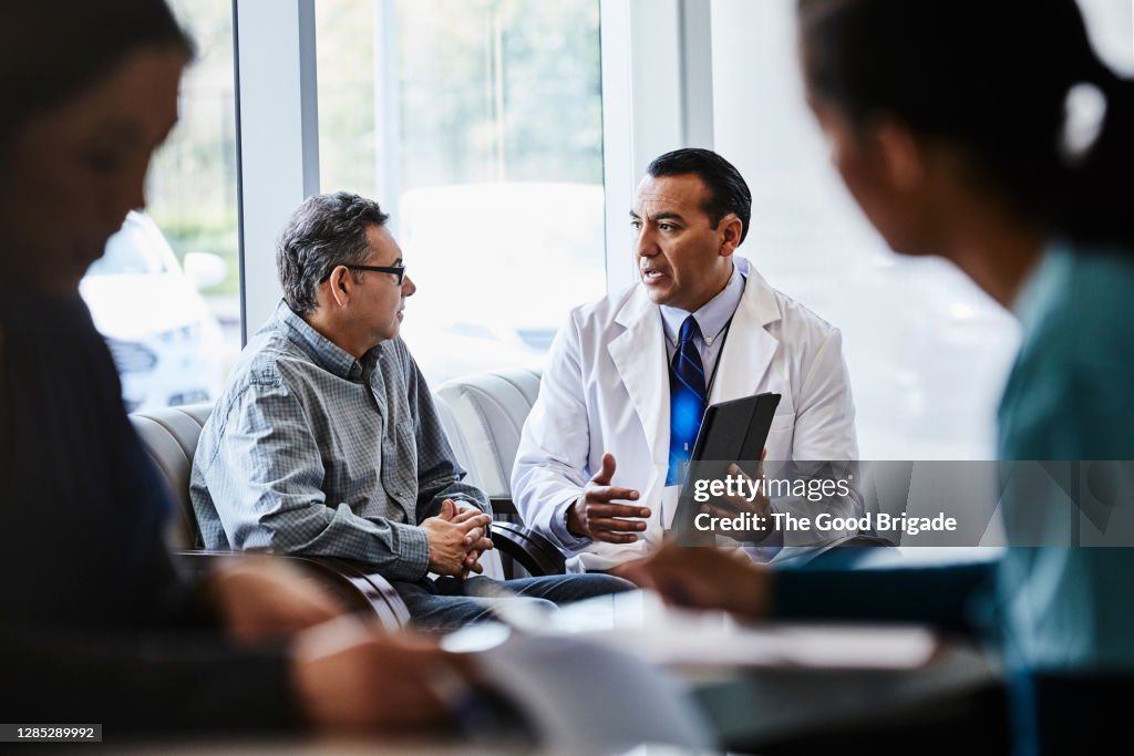 Male doctor discussing with patient at lobby of medical clinic