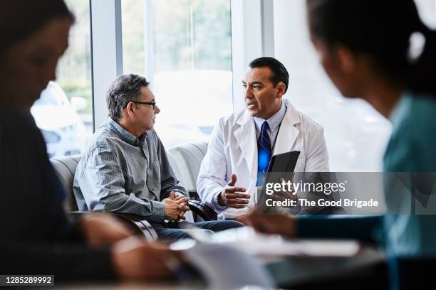 male doctor discussing with patient at lobby of medical clinic - man talking to doctor bildbanksfoton och bilder