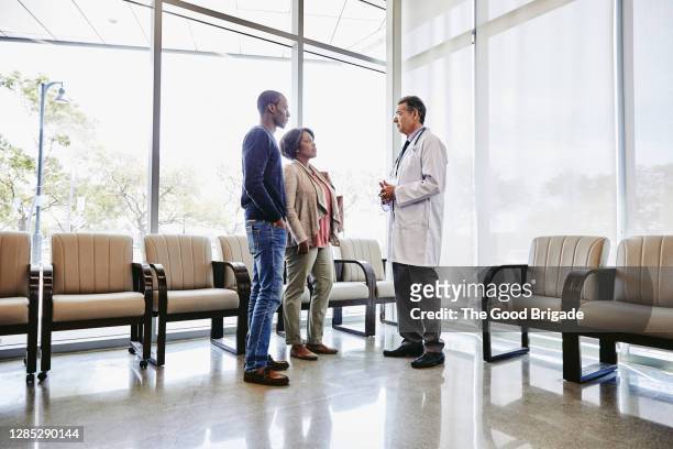 doctor talking to mother and son in hospital waiting room - patient room stockfoto's en -beelden