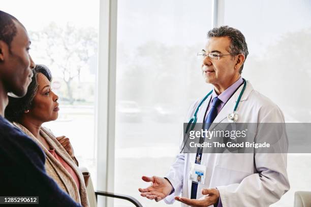 doctor speaking to mother and son in waiting room - doctor and patient talking imagens e fotografias de stock
