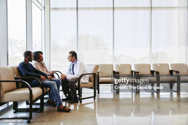 doctor discussing with family while sitting hospital waiting room - severe illness stock pictures, royalty-free photos & images