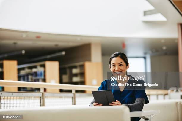 portrait of happy female nurse holding digital tablet while taking a break - happy ipad beautiful stockfoto's en -beelden