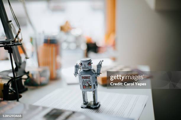 little tin robot on child studio desk - opwindspeeltje stockfoto's en -beelden