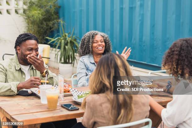 diverse friends enjoy hearty laugh during lunch - social distancing restaurant stock pictures, royalty-free photos & images
