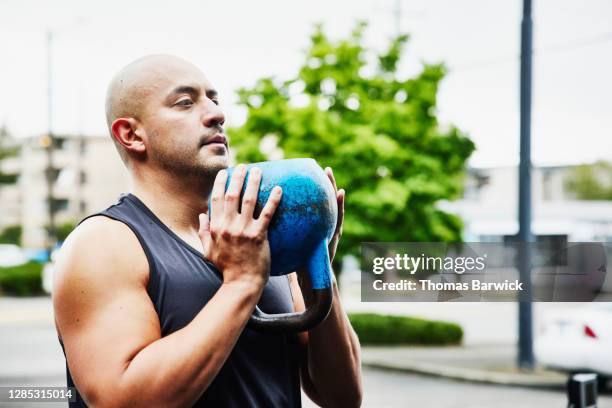man doing kettlebell squats during outdoor workout - waist up stock pictures, royalty-free photos & images