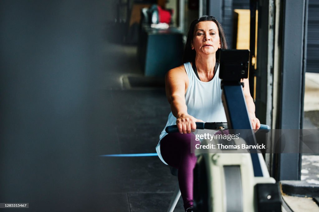 Mature woman working out on rowing machine in gym