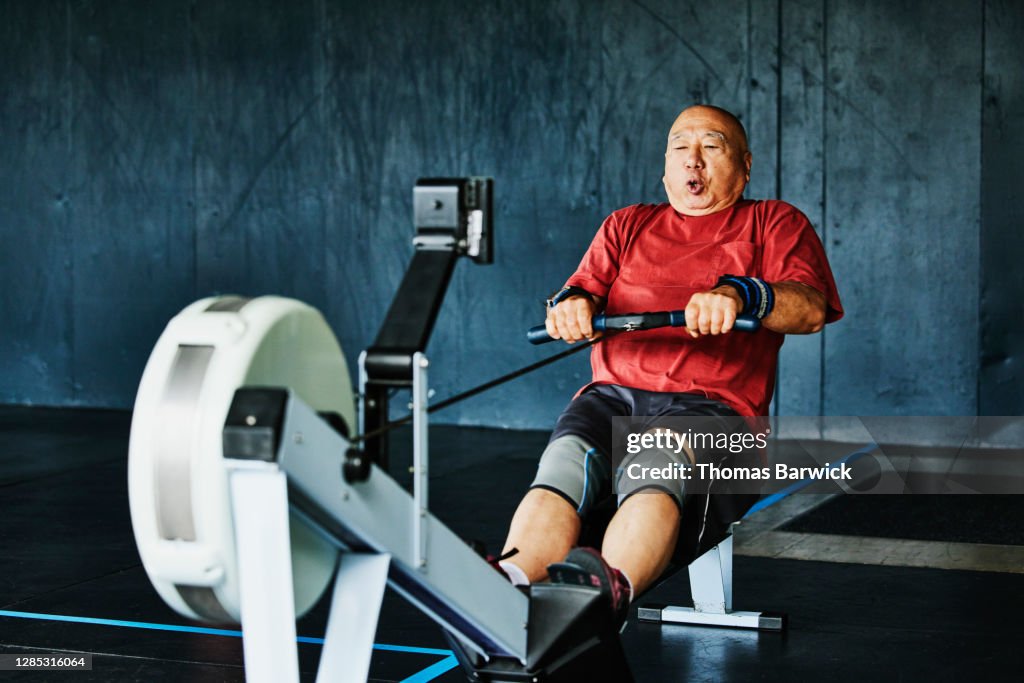 Senior man working out on rowing machine in gym