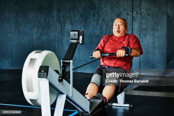 senior man working out on rowing machine in gym - toughness man stock pictures, royalty-free photos & images