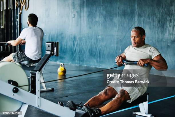 mature man working out on rowing machine in gym - sports training facility stock pictures, royalty-free photos & images