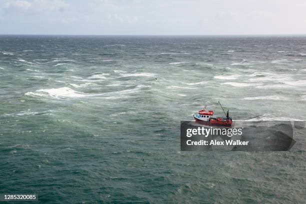 aerial view of small fishing boat in open ocean - fischkutter stock-fotos und bilder