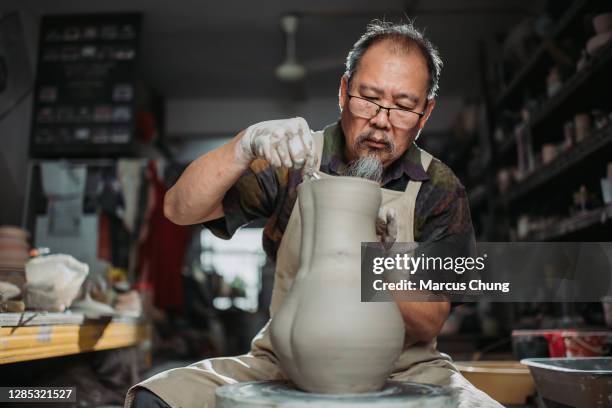 asiatische chinesische senior mann ton künstler machen keramik auf einem sich drehenden keramikrad in seinem handwerksstudio - sculptor stock-fotos und bilder