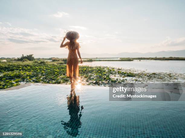 vrouw die bij de rand van infinity pool loopt dat van luxe vakanties geniet - infinity loop stockfoto's en -beelden