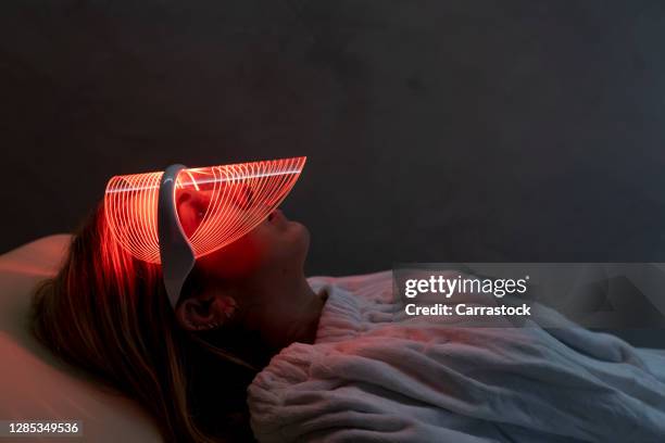 close-up of woman wearing medical led regeneration mask in wellness and care room - protective face mask stock pictures, royalty-free photos & images