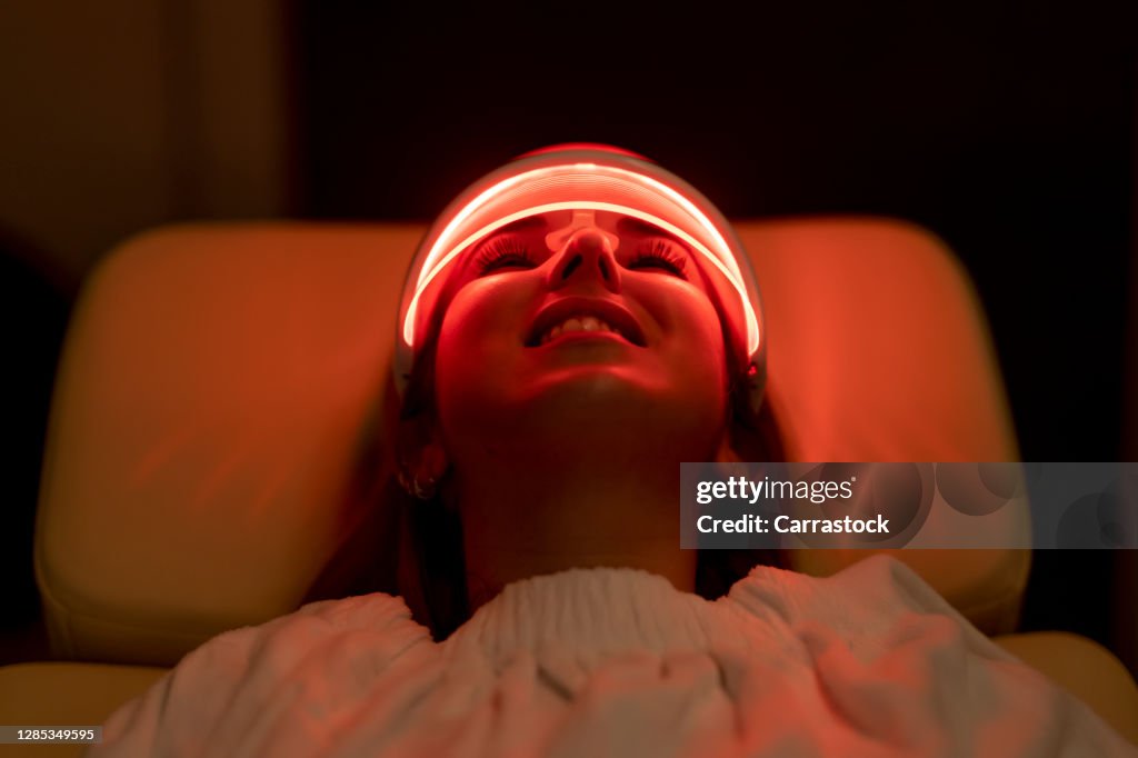 Close-up of woman wearing medical led regeneration mask in wellness and care room