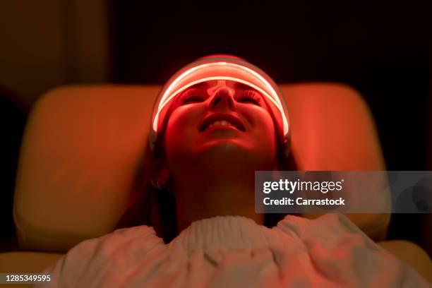 close-up of woman wearing medical led regeneration mask in wellness and care room - máscara facial imagens e fotografias de stock
