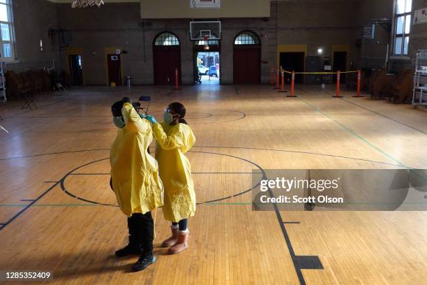 Workers suit up in personal protective equipment as they prepare to open a COVID-19 test site run by CORE at St. Benedict the African Catholic Church...