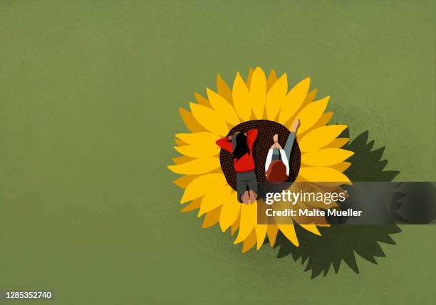 teenage girls relaxing on large sunflower on green background - imagination kids stock illustrations