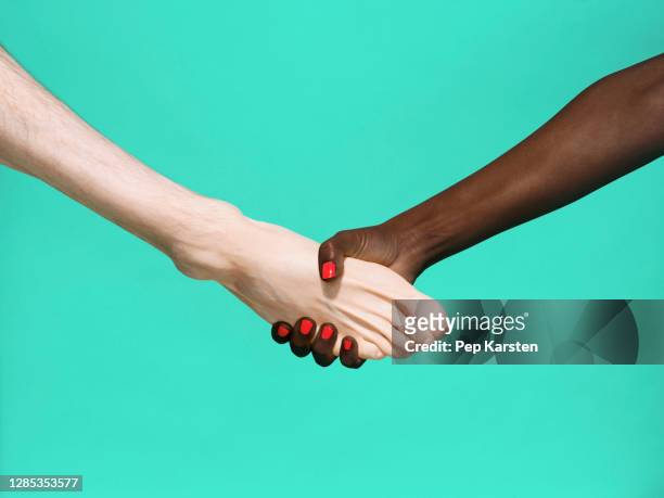 multiethnic foot and hand shake on green background - heels hand stock-fotos und bilder