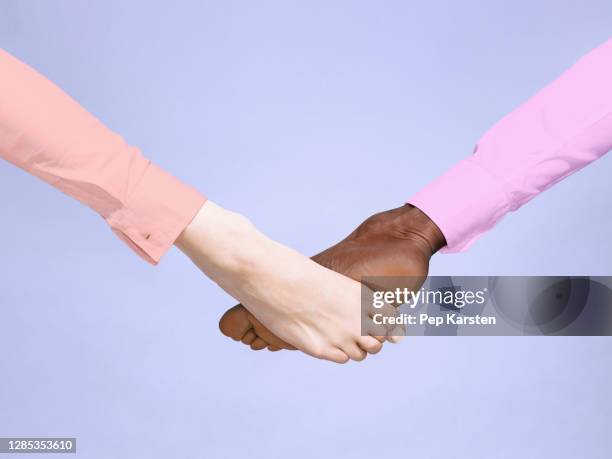 multiethnic barefoot foot bump on purple background - handshake abstract stock pictures, royalty-free photos & images