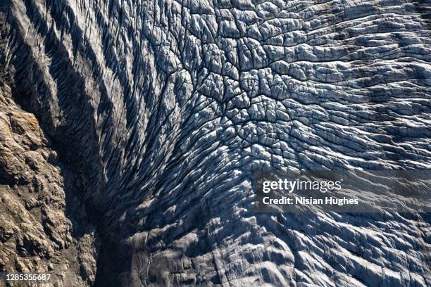 aerial flying over aletsch glacier looking directly down at the ice in switzerland at sunrise - aletsch glacier stock pictures, royalty-free photos & images