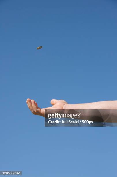 cropped hand tossing a coin against clear blue sky - flipping a coin stock pictures, royalty-free photos & images