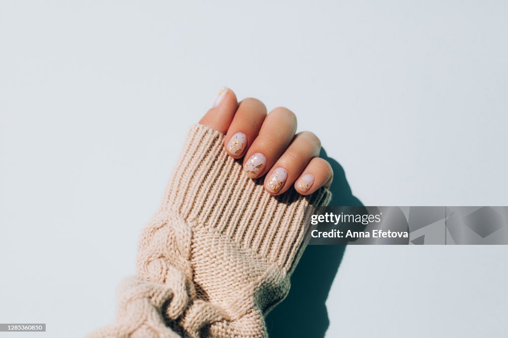 Woman's hand in warm sweater showing manicure