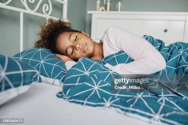 ein kleines mädchen schläft im bett - black man sleeping in bed stock-fotos und bilder