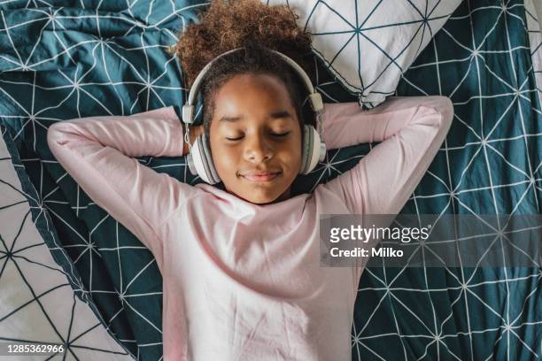 ein kleines afroamerikanisches mädchen genießt ihre freizeit zu hause - listening stock-fotos und bilder