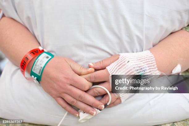 a pregnant mother hugs a pillow during her epidural injection - namensband stock-fotos und bilder