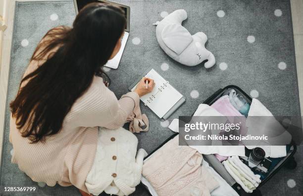 eine schwangere frau bereitet eine tasche für das krankenhaus vor - taschen stock-fotos und bilder