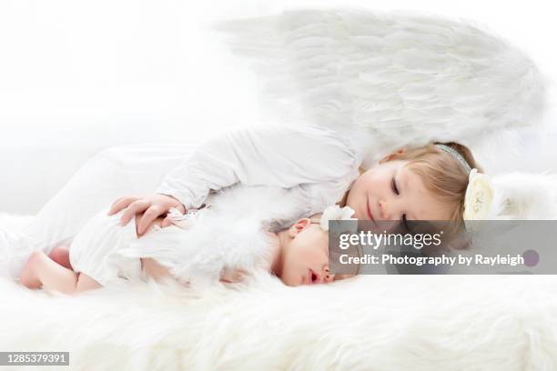 a newborn baby with her big sister, both dressed as angels - baby angel wings stock pictures, royalty-free photos & images