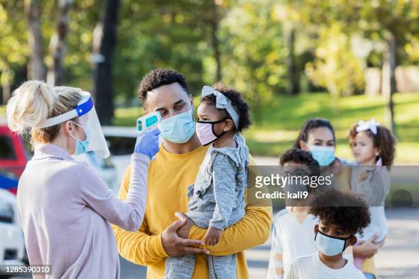family waiting in line at covid temperature checkpoint - temperature checkpoint stock pictures, royalty-free photos & images