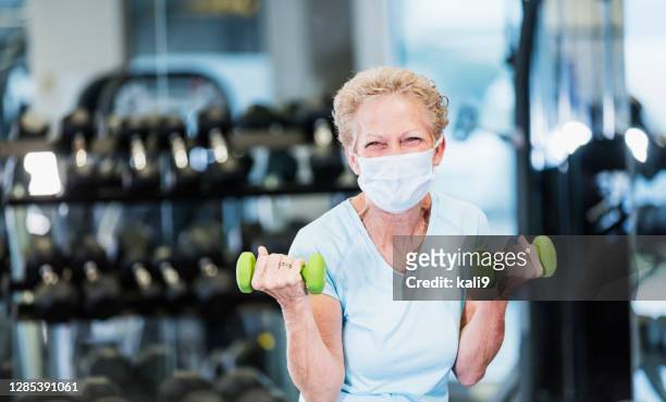 senior woman working out at the gym, wearing face mask - practicing stock pictures, royalty-free photos & images